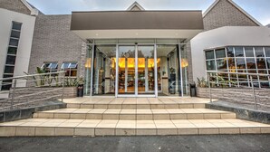 A modern building with a glass entrance, steps leading up to it, and a sign that reads "CITY LODGE".