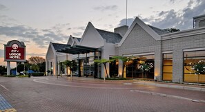 A hotel with a modern architectural design, featuring a prominent entrance with a covered walkway, large windows, and a landscaped area with plants. - City Lodge Johannesburg Airport, Barbara Road (Edenvale)