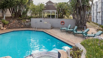 Una piscina al aire libre, sillones reclinables de piscina