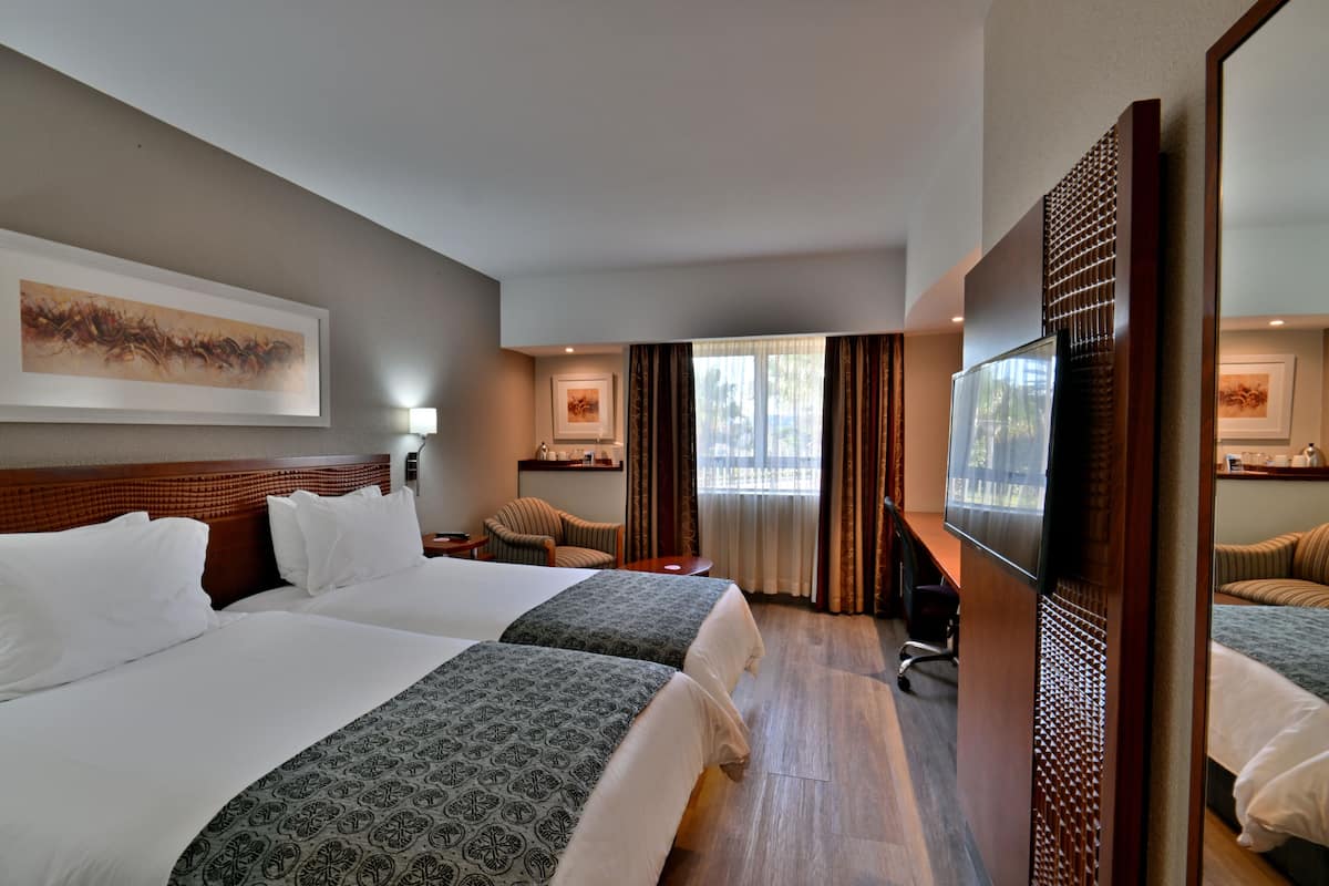 Una habitación de hotel con dos camas, televisión, escritorio y silla.
