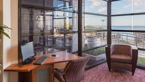 Et moderne kontor med skrivebord, computer og stol, med udsigt over et smukt landskab og en balkon.