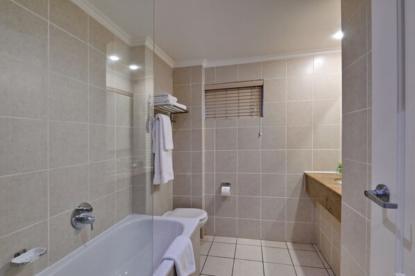 Un baño moderno con bañera, toallero y ventana con persianas.
