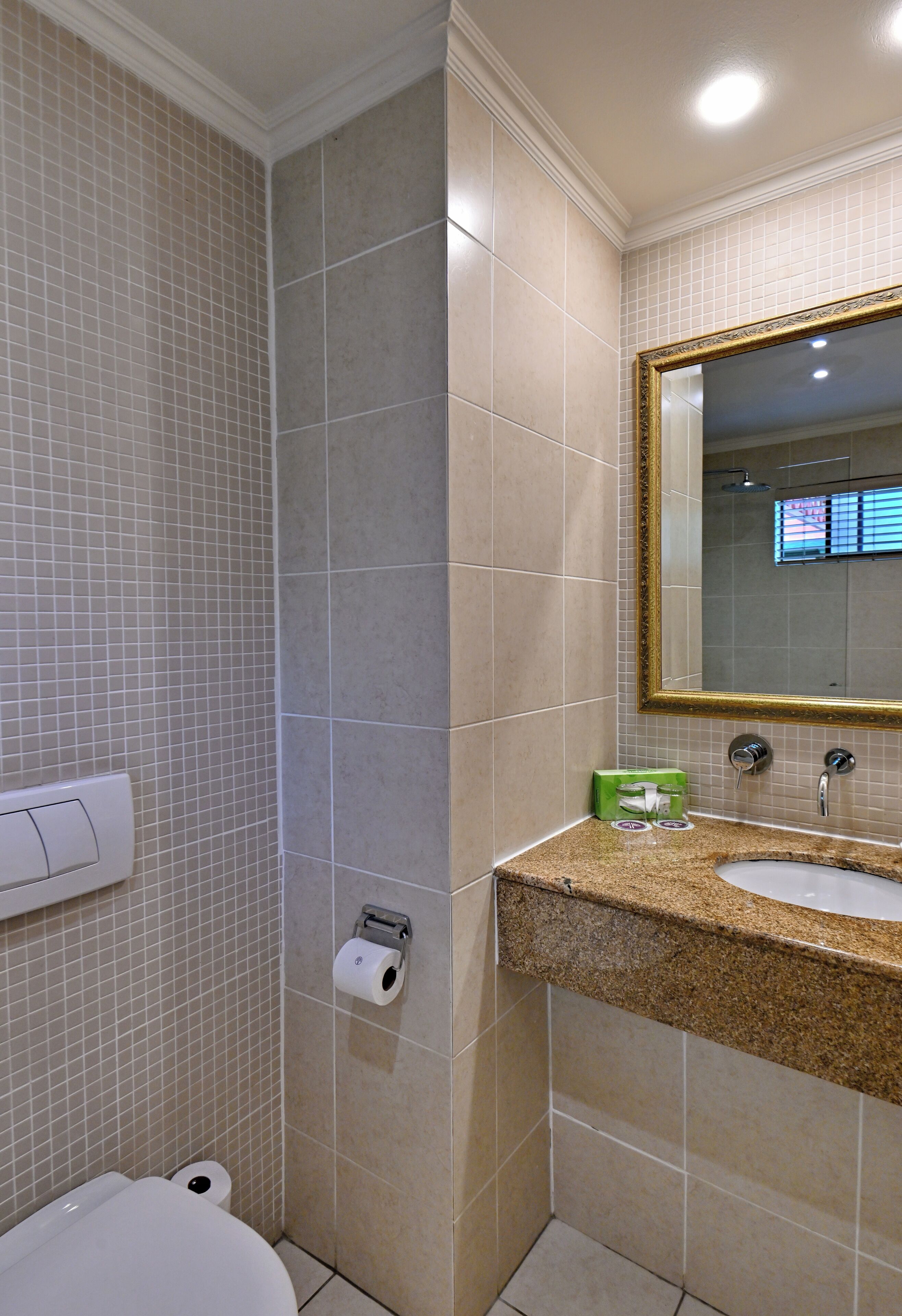 A bathroom with a toilet, sink, and mirror.