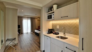 A compact kitchen with a microwave, coffee maker, and a sink. There is a small refrigerator and a drying rack. The room has a wooden floor and a tiled backsplash. - Courtyard Hotel Sandton (Sandton)