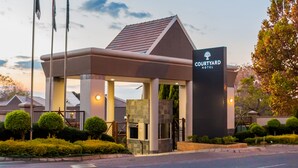 A Courtyard Hotel entrance with a modern design, including a covered waiting area and a prominent sign. - Courtyard Hotel Sandton (Sandton)