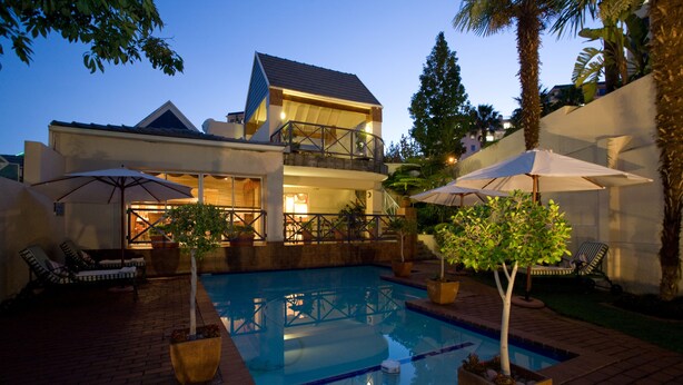 A two-story house with a swimming pool, outdoor furniture, and potted plants. - Courtyard Hotel Sandton (Sandton)