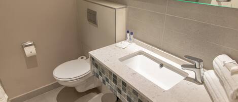 A bathroom with a toilet, sink, and mirror.
