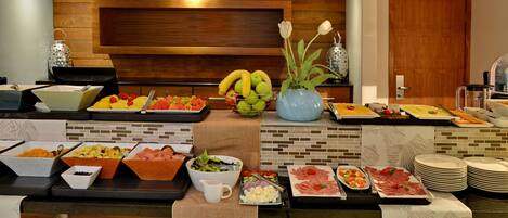 A buffet with various food items and a decorative vase with flowers.