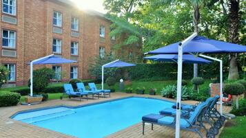 Una piscina al aire libre, sombrillas, sillones reclinables de piscina