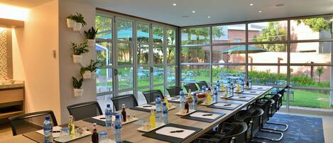 A conference room with a long table, chairs, water bottles, and papers.