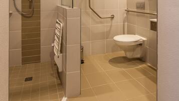 Un baño moderno con ducha, inodoro y secador de manos.