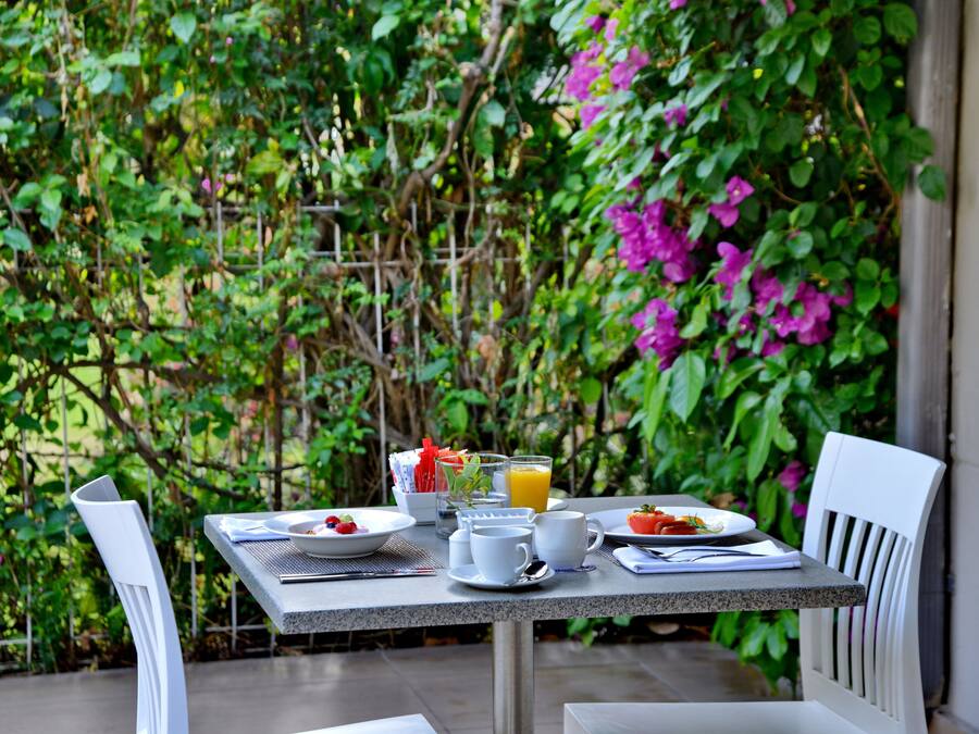 A table set for breakfast with a view of lush greenery and flowers.