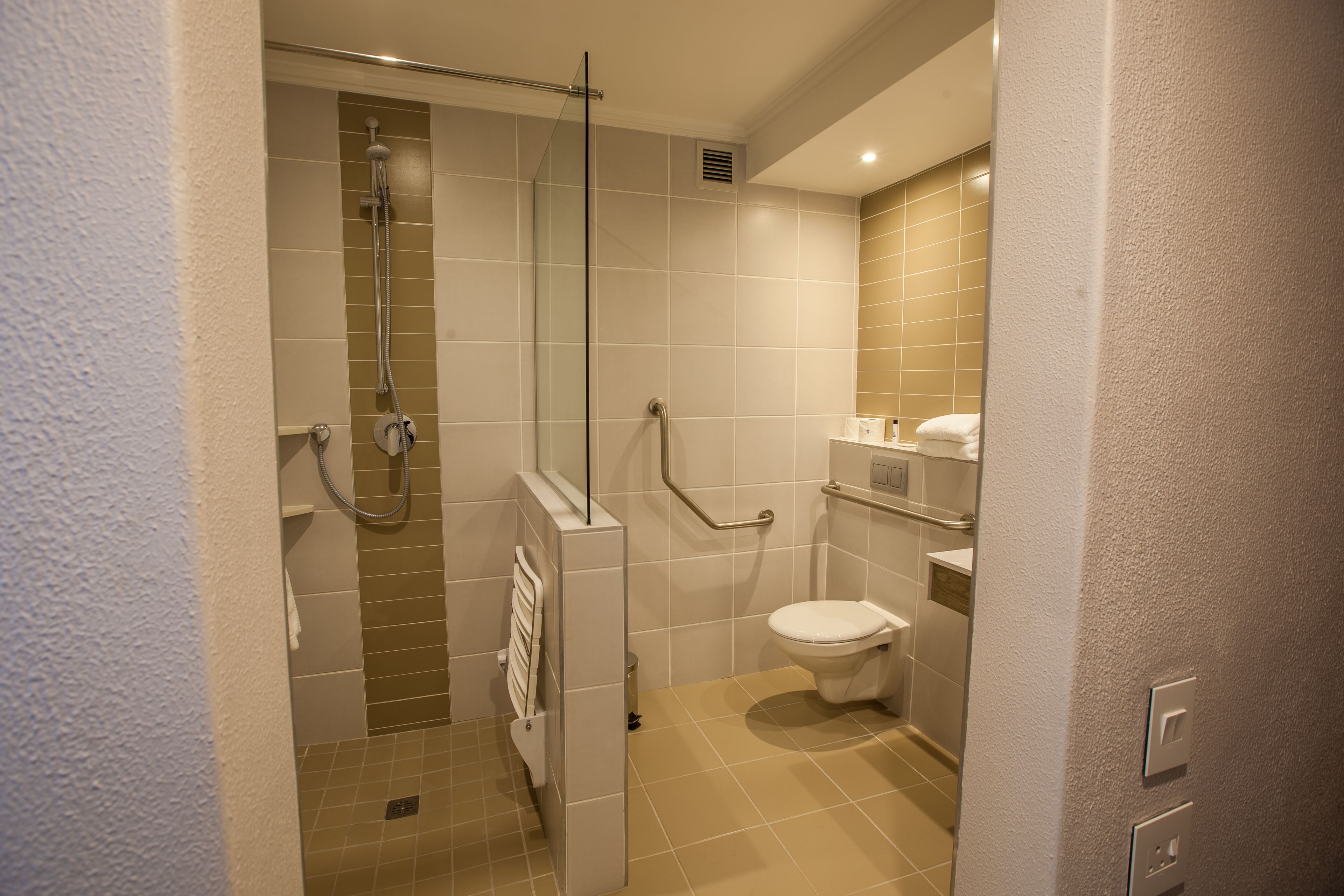 Een kleine, moderne badkamer met een douche, toilet en een glazen scheidingswand.
