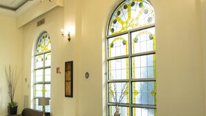 A spacious lobby with a chandelier, two sofas, a coffee table, and large windows with stained glass. - Best Western Centro Monterrey (Monterrey)