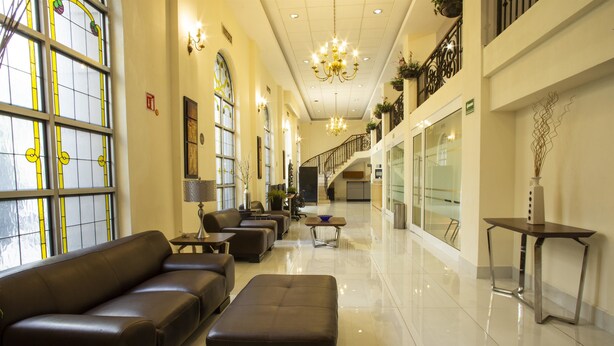 A spacious lobby with a long reception desk, leather seating, and a chandelier. - Best Western Centro Monterrey (Monterrey)