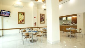 A clean, well-lit restaurant with multiple tables and chairs, a television mounted on the wall, and a kitchen area visible through an open counter. - Best Western Centro Monterrey (Monterrey)