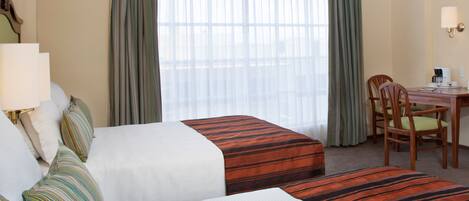Habitación de hotel con dos camas, un escritorio y una silla.