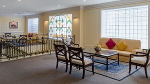 A spacious lobby with a seating area, a staircase, and a large stained glass window. - Francia Aguascalientes (Aguascalientes)