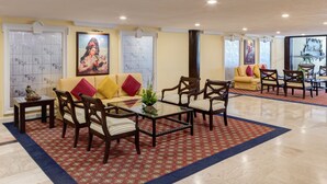 A hotel lobby with a central seating area, a large window, and a decorative wall. - Francia Aguascalientes (Aguascalientes)
