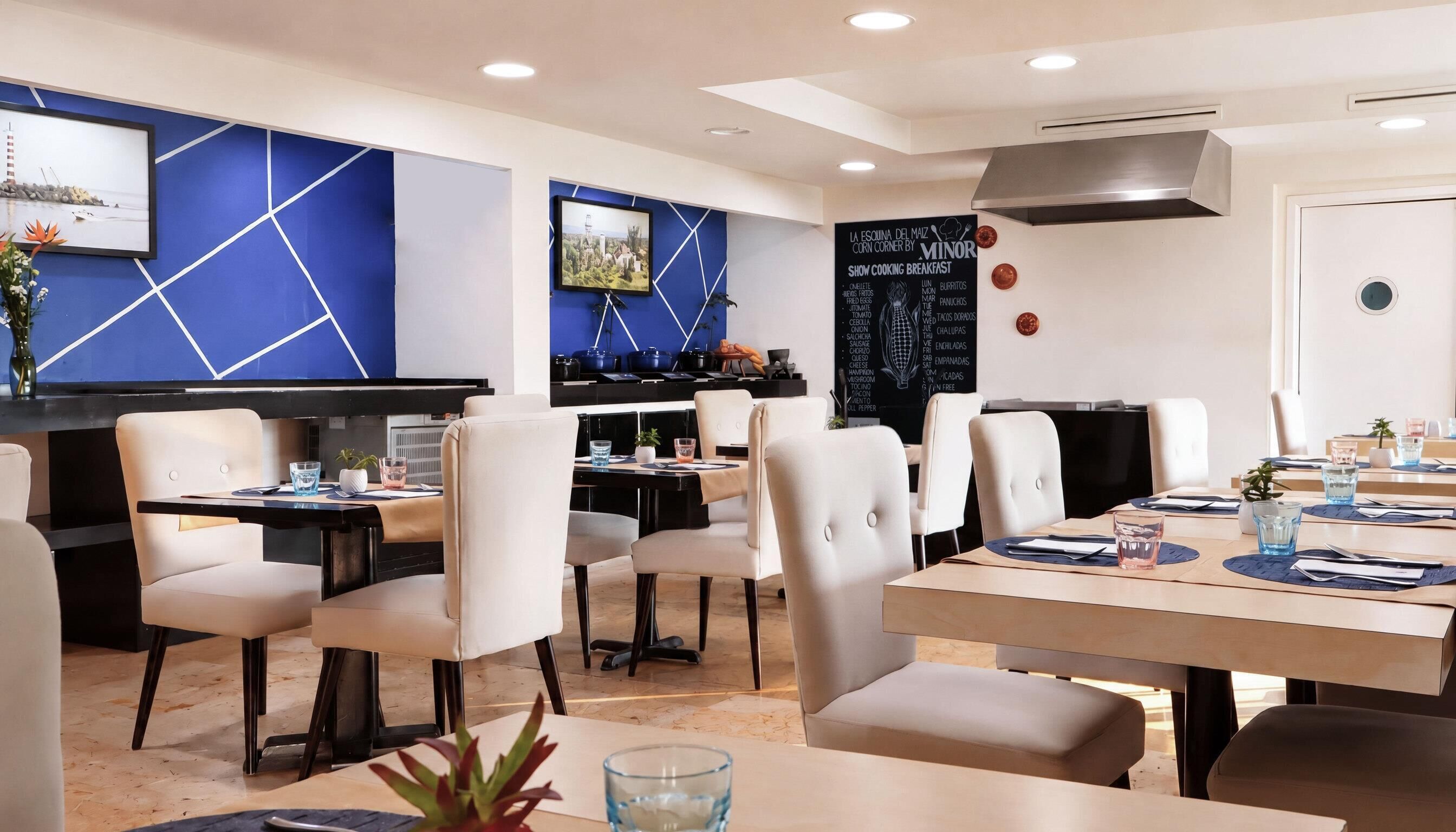 A modern restaurant with a blue geometric wall design, multiple dining tables, and chairs.