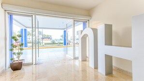 Un moderno vestíbulo de hotel con entrada por puerta de vidrio, una planta en maceta y un piso limpio y pulido.