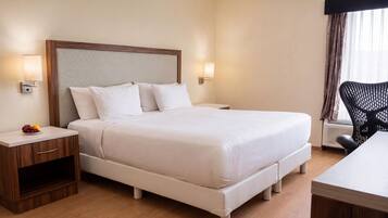 Una camera d'albergo con un letto grande, comodini, una scrivania e una sedia.