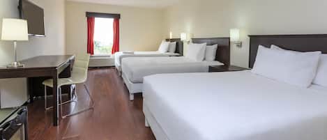 Habitación de hotel con dos camas, un escritorio, una silla y un televisor.