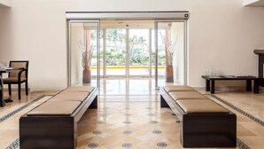 Un vestíbulo de hotel con un área de estar central, una recepción y vistas al exterior.