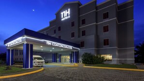Un hotel de diseño moderno, con un letrero destacado que dice "NH Hotels" y "TH COATZACOALCOS".