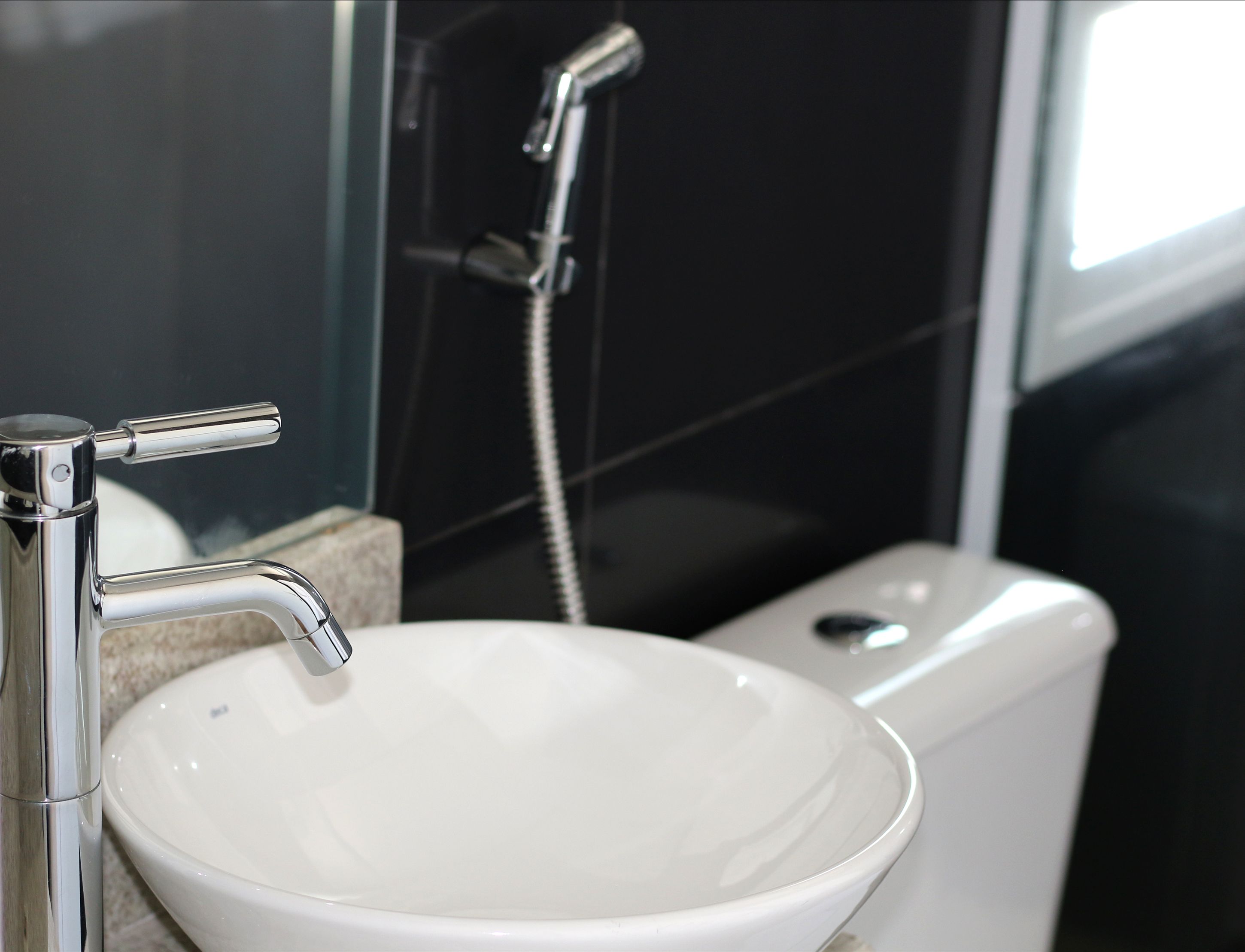 Een badkamer met een wit wastafel, een chromen kraan en een handdouche.