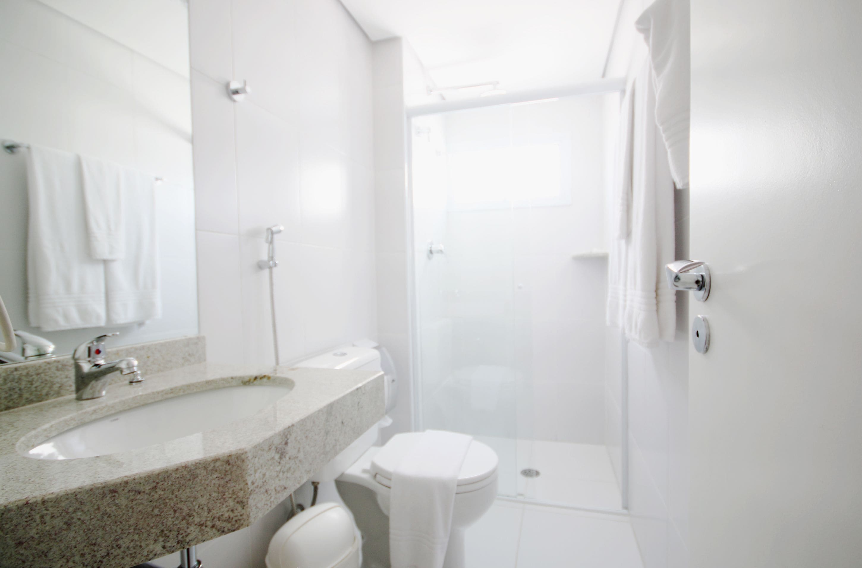 Een moderne badkamer met een wastafelblad van graniet, een toilet en een douchecabine.