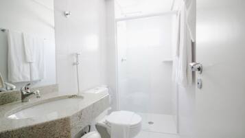 Een moderne badkamer met een wastafelblad van graniet, een toilet en een douchecabine.