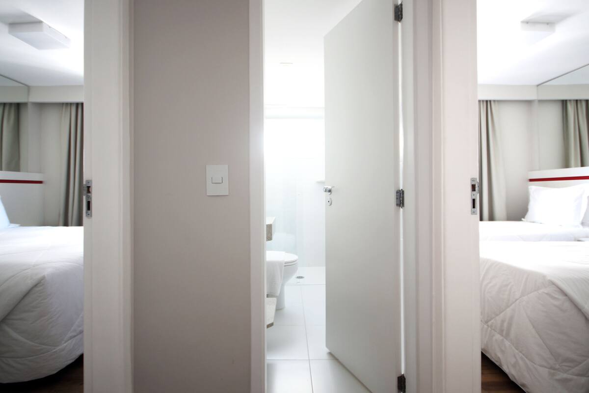 Une chambre d’hôtel comprenant un lit, une salle de bain et une porte donnant sur une autre pièce.