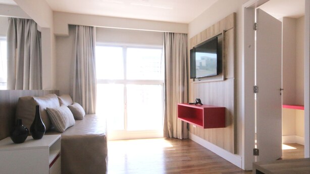 Een moderne woonkamer met een bank, een flatscreen-tv aan de wand en een houten vloer.