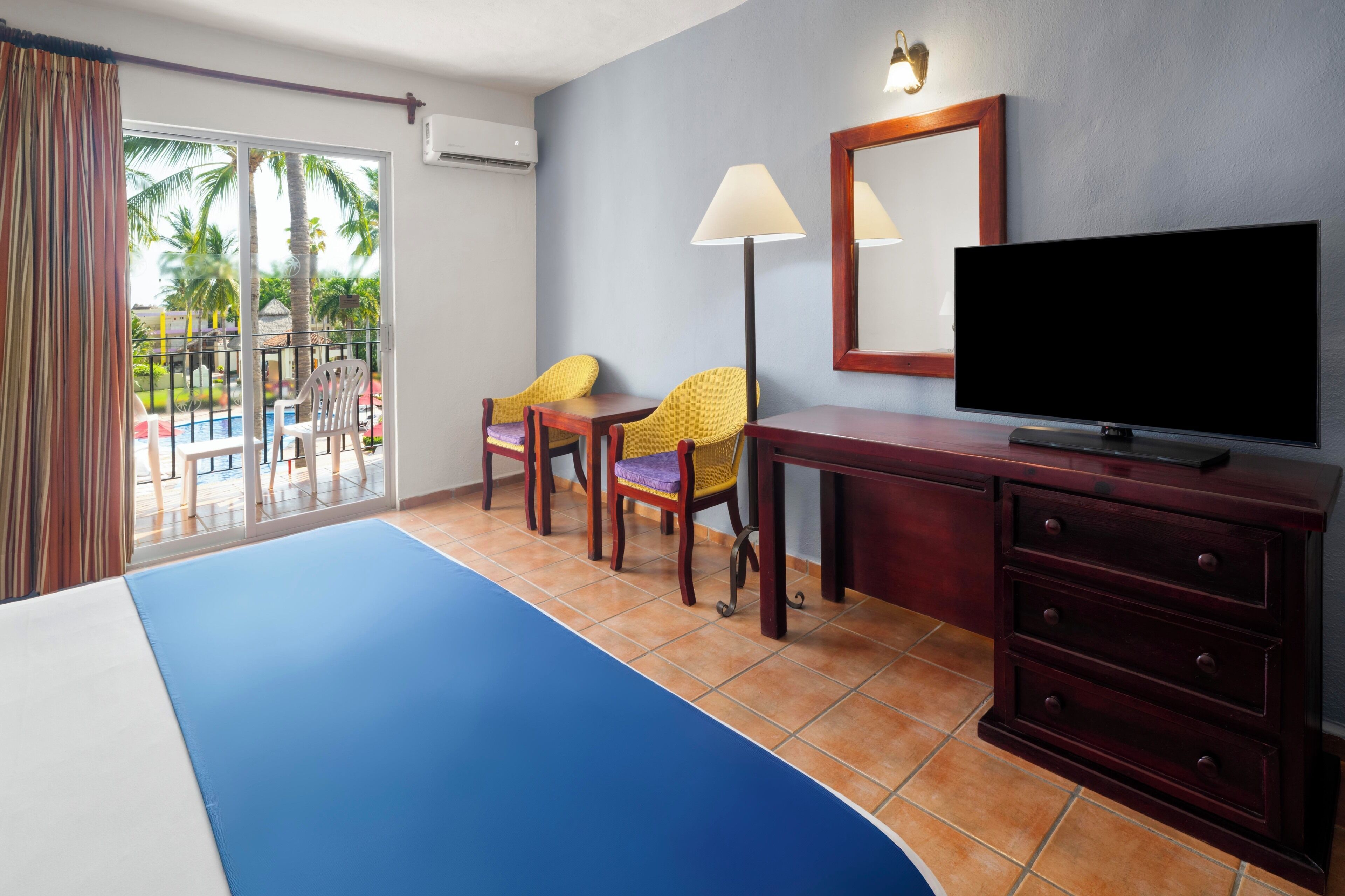 Una habitación de hotel con cama, televisor, escritorio y dos sillas.