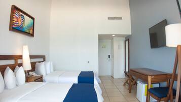 A hotel room with two beds, a desk, a chair, a television, and a painting on the wall.