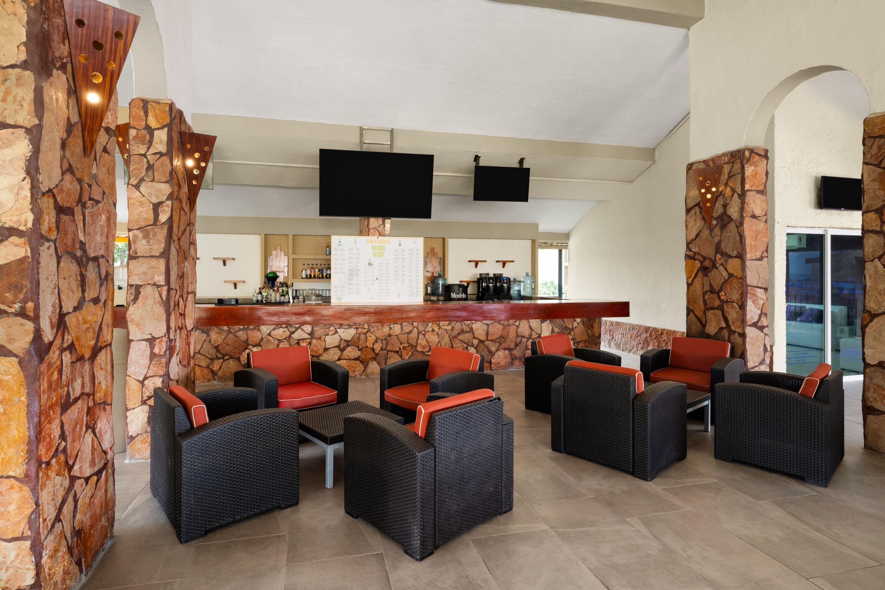 A lobby with stone walls, wicker furniture, a bar area, and a flat-screen TV mounted on the wall.