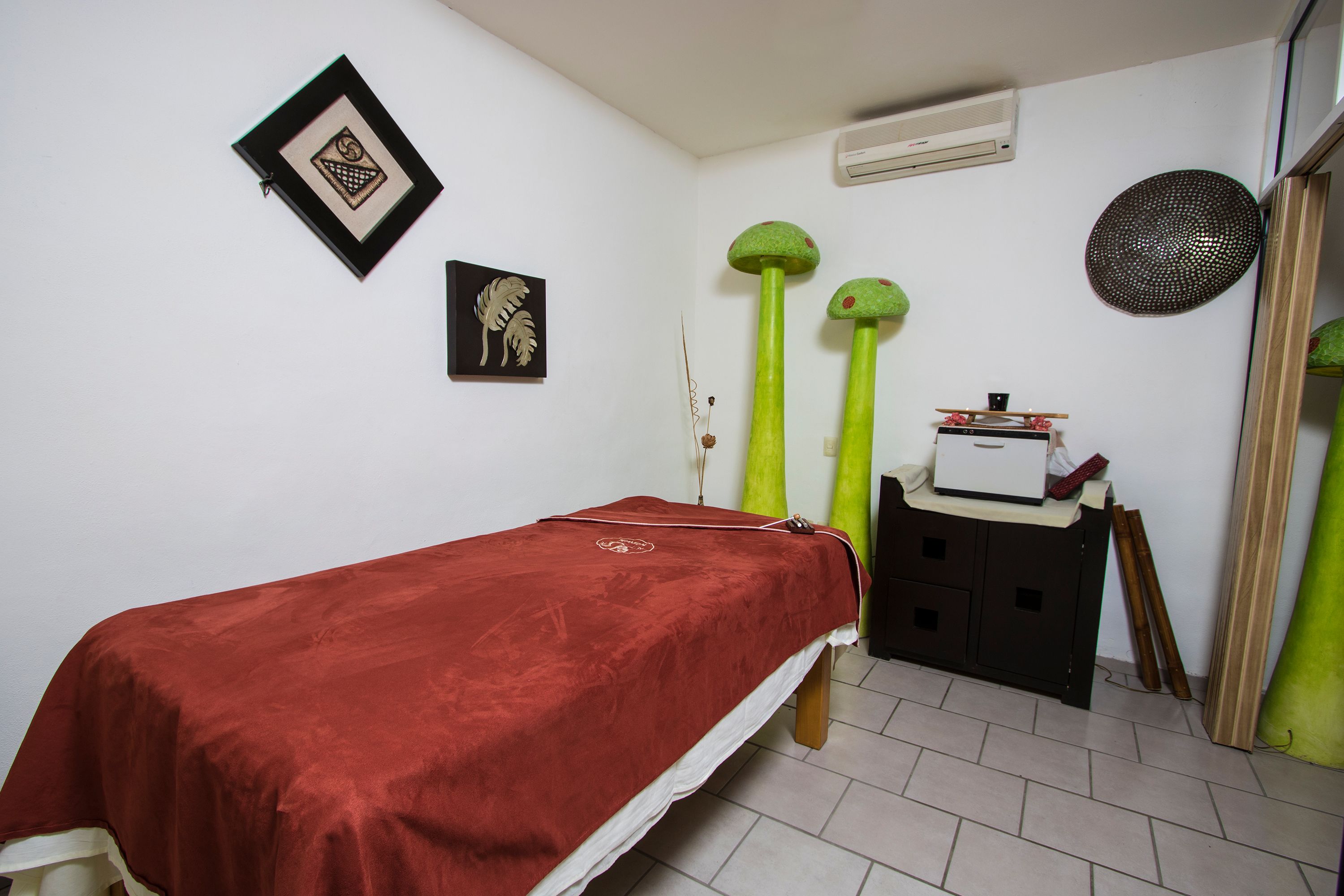 Una habitación con una cama, un mueble pequeño y dos objetos que parecen plantas.