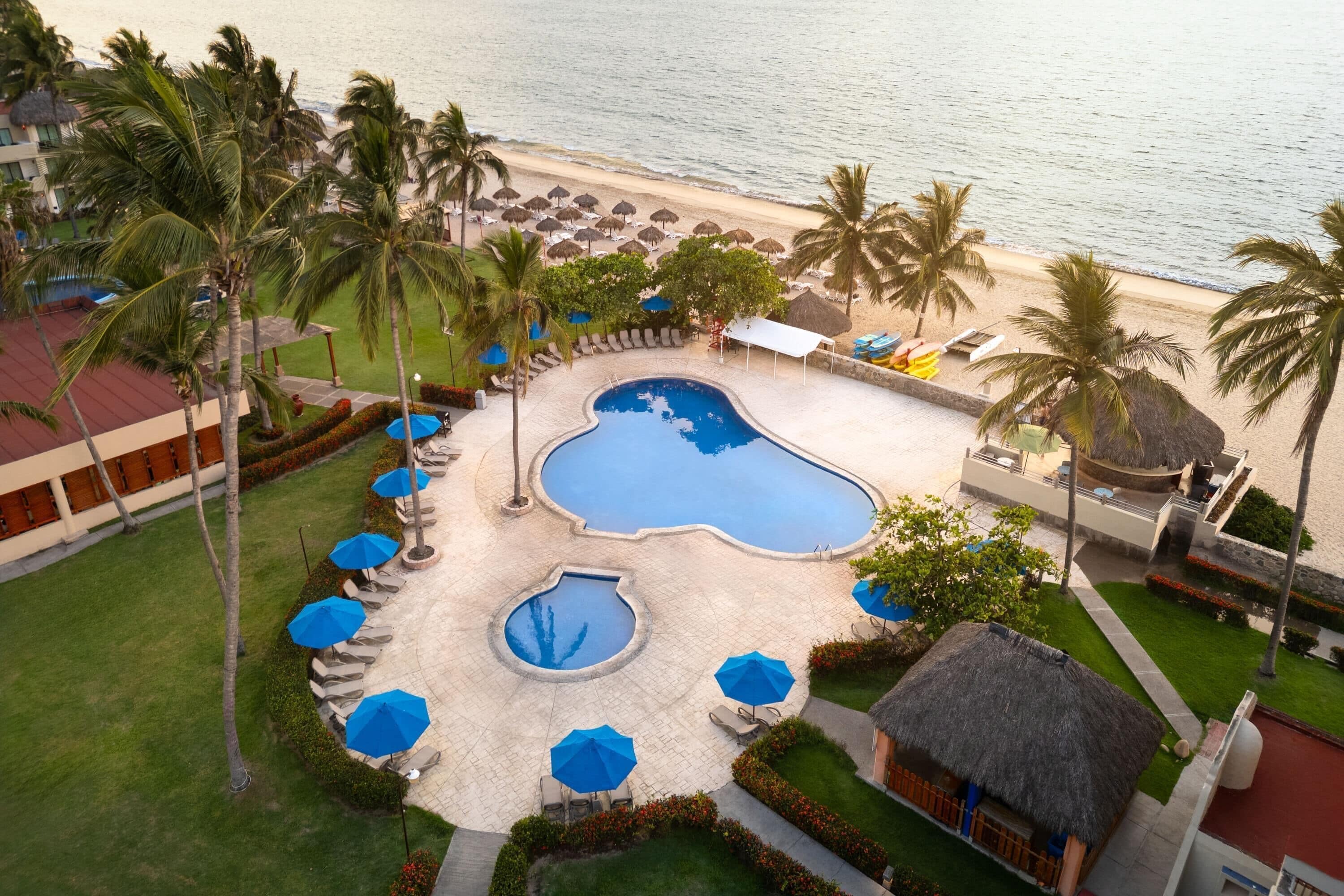 Un resort con piscina, palmeras y vista al mar.