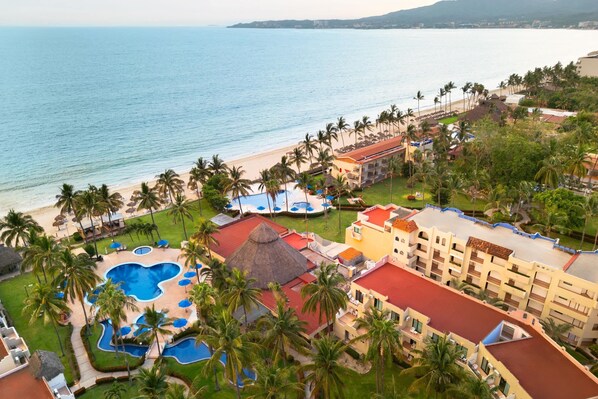 A resort with a large pool area, multiple swimming pools, and a beach.
