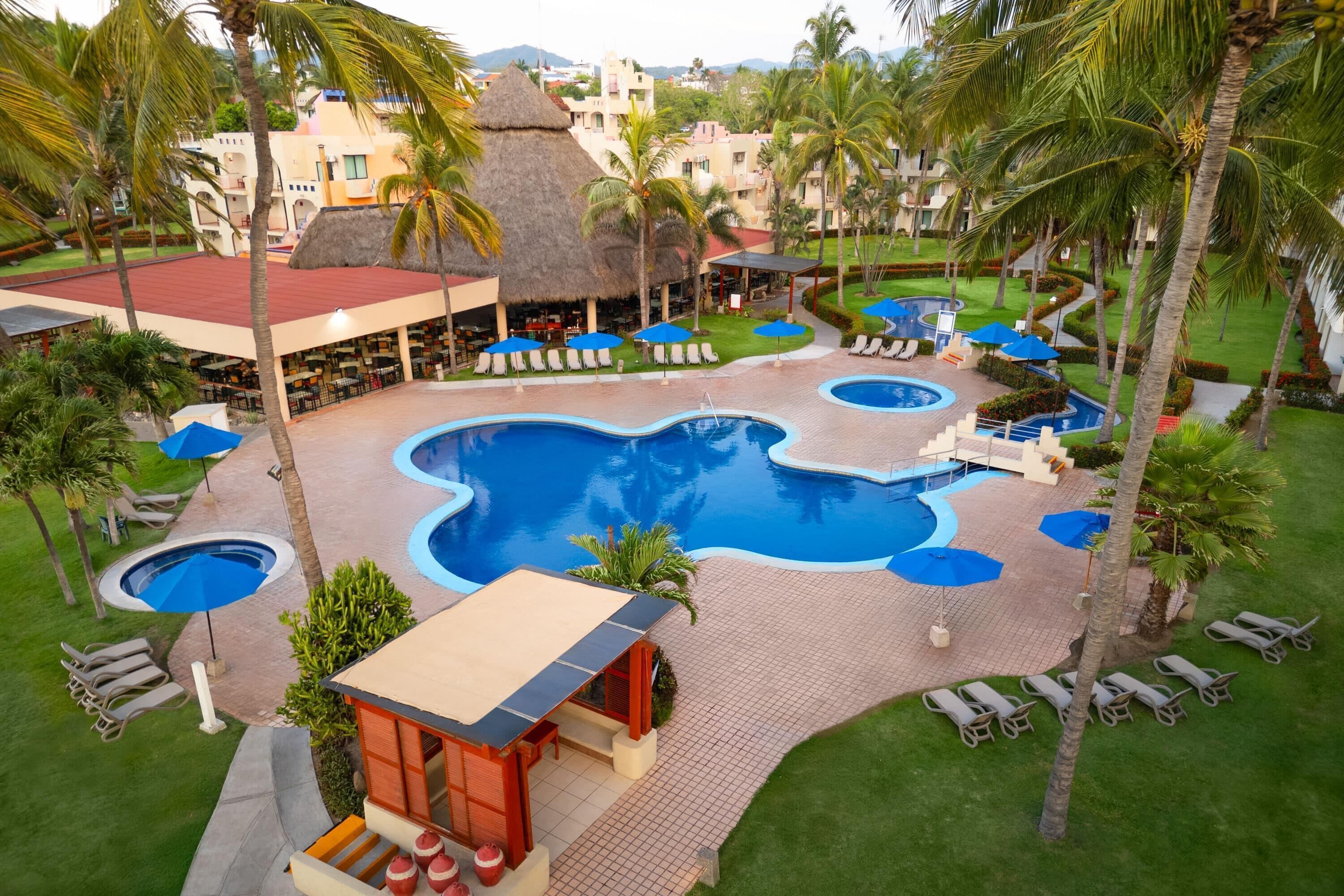 Un complexe hôtelier doté de plusieurs piscines, d’espaces de détente et de palmiers.