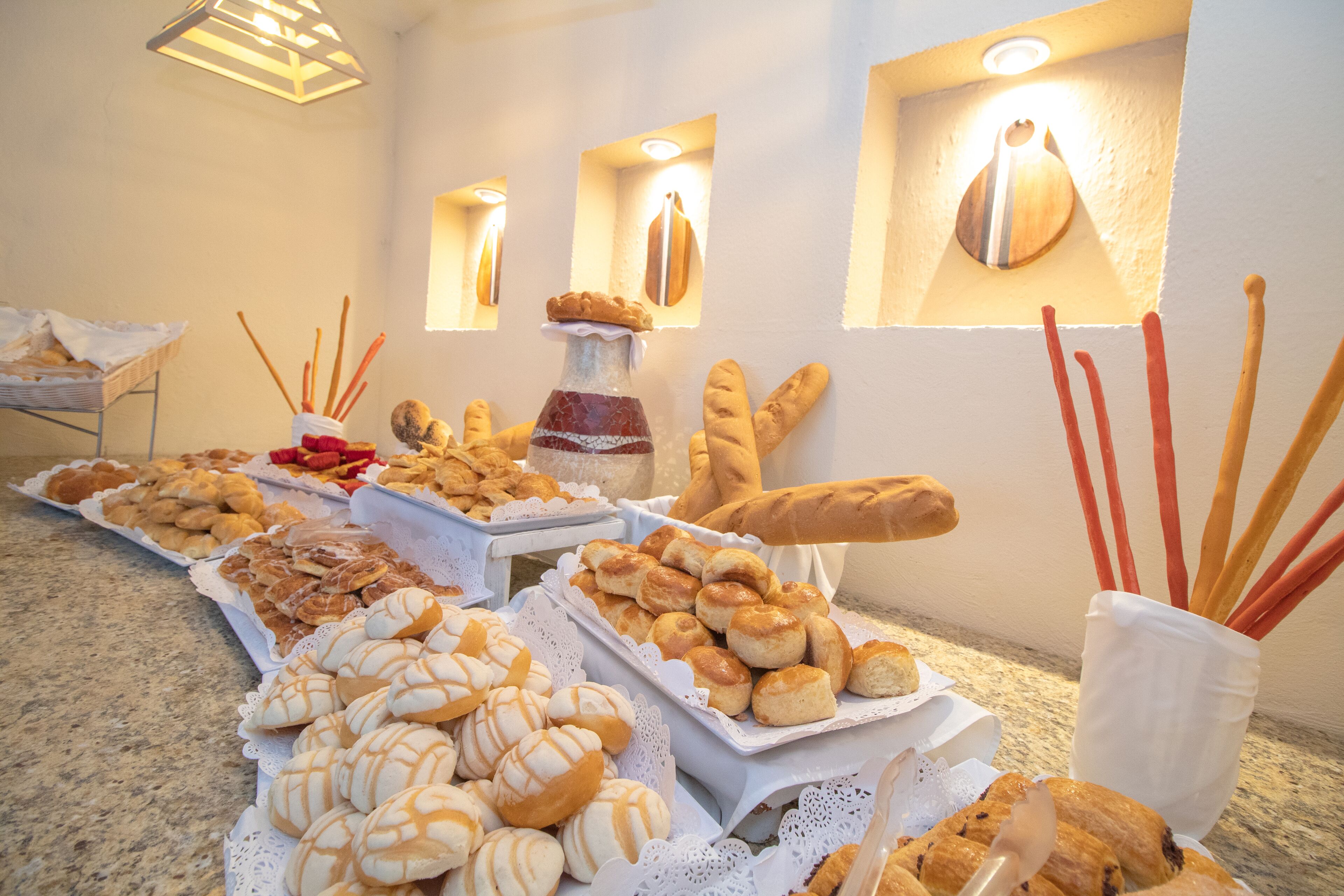 A buffet table with various baked goods and breadsticks.