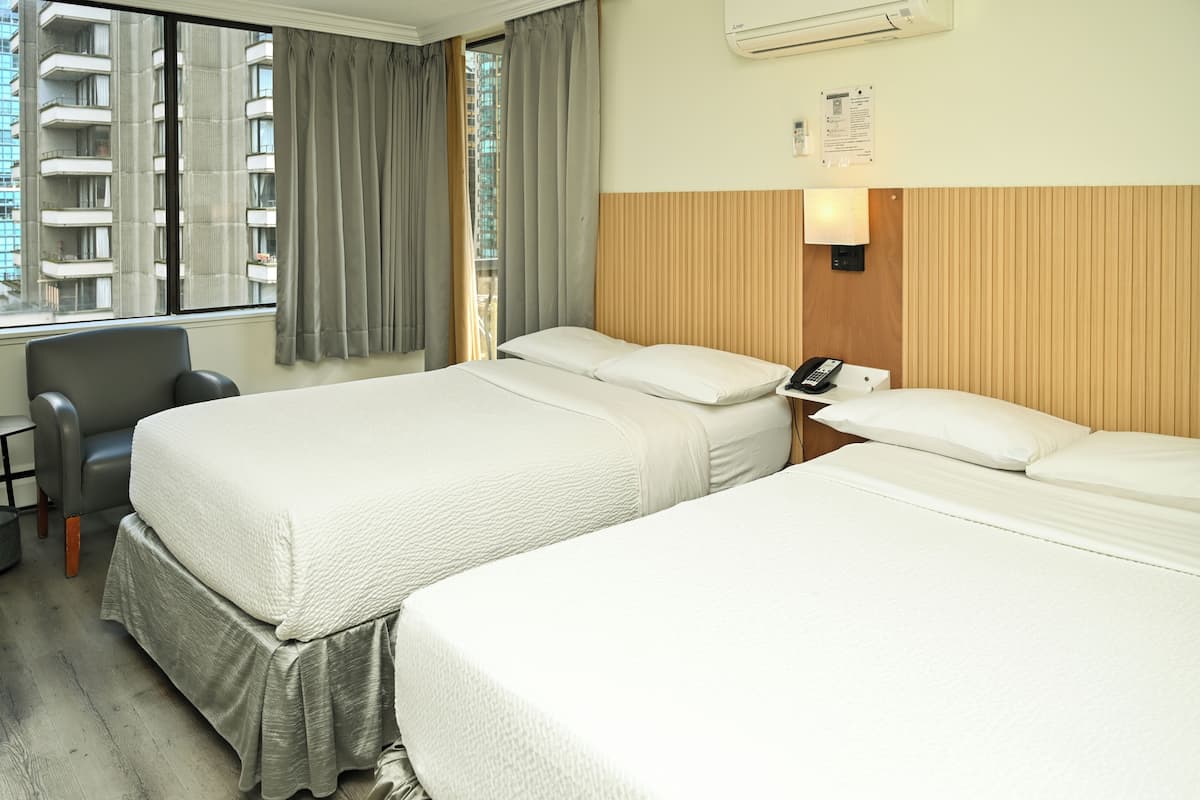 A hotel room with two beds, a desk, a chair, a telephone, and a window with curtains.