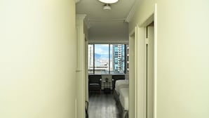 Un pasillo estrecho que conduce a una habitación con una cama, una mesita y dos sillas.