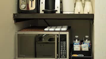 Eine Küchenzeile mit Kaffeemaschine, Mikrowelle und Kühlschrank.