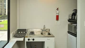 Una kitchenette compacta con estufa, lavamanos y microondas.