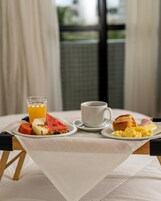 Una mesa de desayuno con un vaso de jugo de naranja, una taza de café, tostadas, huevos revueltos y diversas frutas.