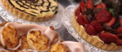 Diversos postres, incluyendo una tarta con diseño en espiral, una tarta con fresas y tartaletas mini.
