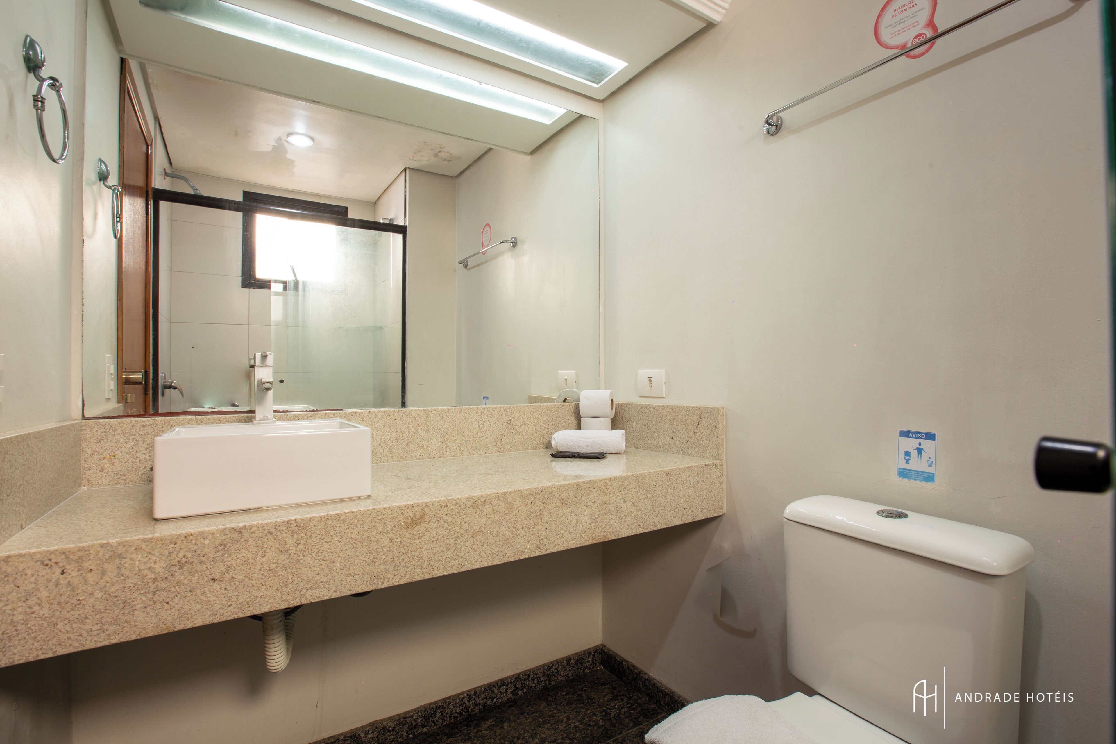 A bathroom with a sink, mirror, towel, and toilet.