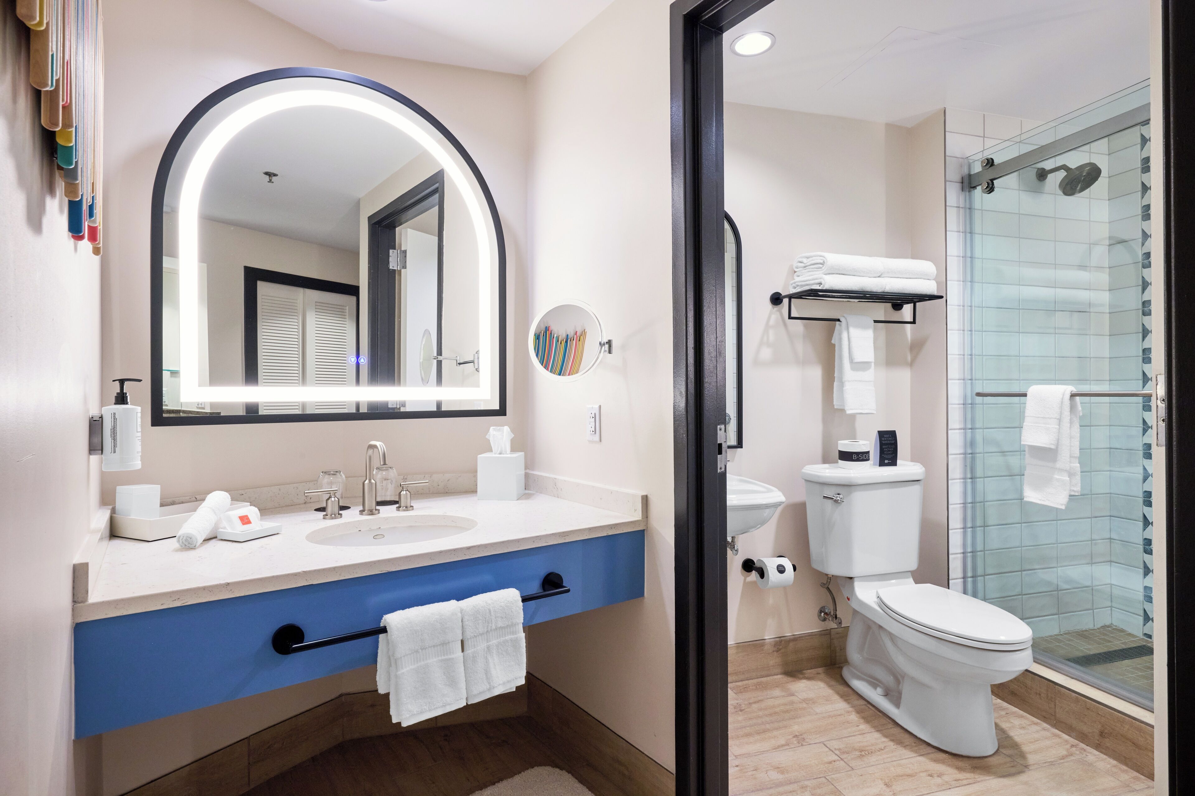 A modern bathroom with a large mirror, dual sinks, a toilet, and a glass-enclosed shower.